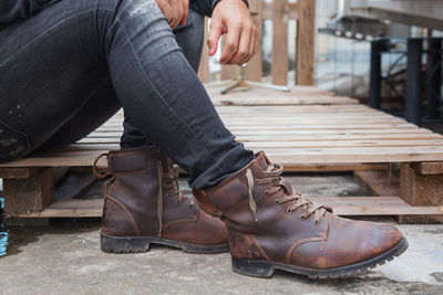 Low section of man wearing shoes while sitting on palette