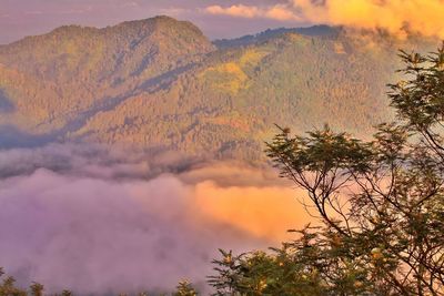 Scenic view of mountains against cloudy sky at sunset