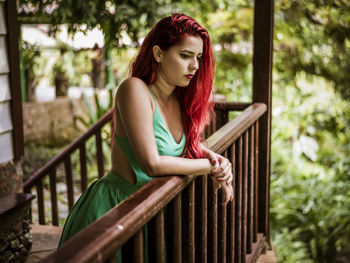 Young woman looking away while sitting on railing