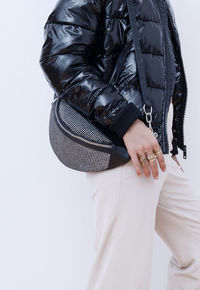 Midsection of woman with bag standing against gray background