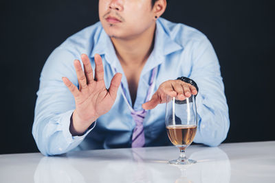 Mid section of a man with drink on table