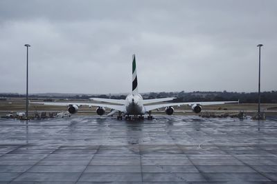 Airplane flying over wet airport against sky during rainy season