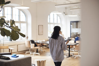 Rear view of female entrepreneur doing video call through smart phone at coworking office