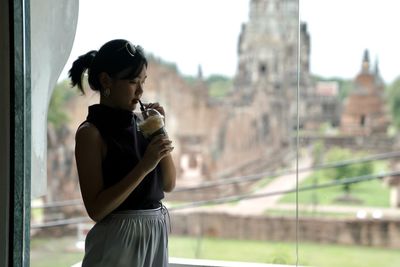 Full length of a young woman drinking outdoors