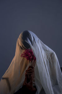 Midsection of woman holding bouquet against white background