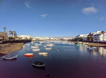 Boats moored in river against sky in city