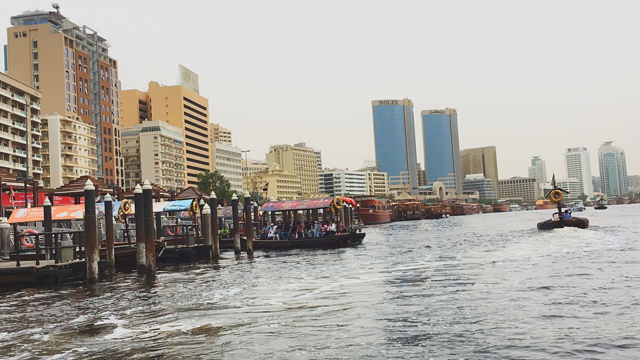 building exterior, water, built structure, architecture, city, nautical vessel, transportation, clear sky, waterfront, mode of transport, copy space, sea, boat, river, cityscape, skyscraper, urban skyline, sky, city life, harbor