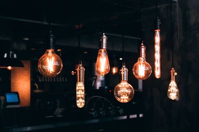 Illuminated light bulbs hanging at night