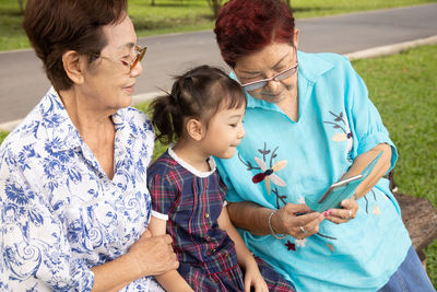 Grandmother showing smart phone to granddaughter at park