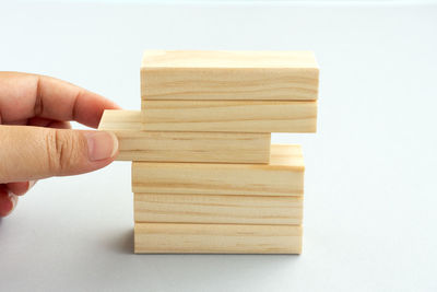 Close-up of hand holding wood against white background
