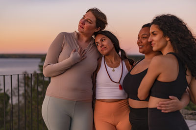Female friends standing with each other at sunset