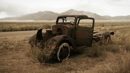 Abandoned vintage car on landscape against sky