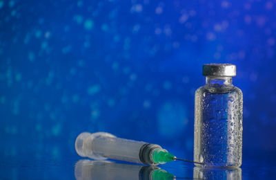 Close-up of glass bottle on table against blue background