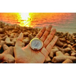 Close-up of woman hand holding sand at beach against sky