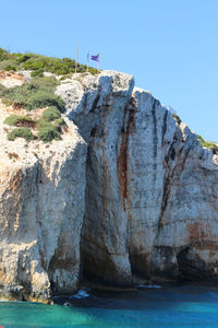 Rock formations by sea against clear blue sky