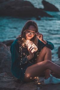 Portrait of young woman sitting by sea