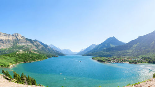 Scenic view of sea and mountains against clear blue sky