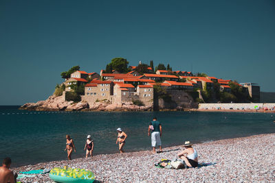 People at beach against clear sky