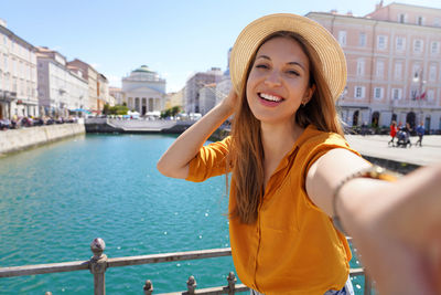 Woman making selfie photo standing on the bridge with beautiful view on trieste city in italy