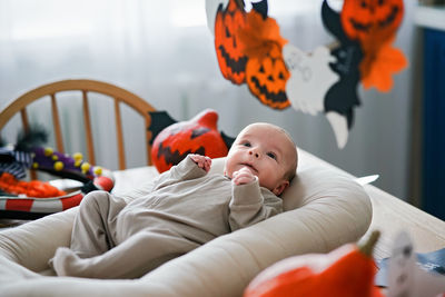 A small child lies surrounded by halloween decorations