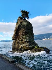 Rock formation on sea shore against sky