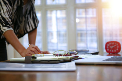 Midsection of woman with umbrella on table