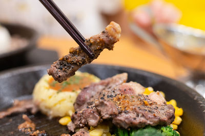 Chopstick take piece of meat over steak with vegetable put on hot plate after cook