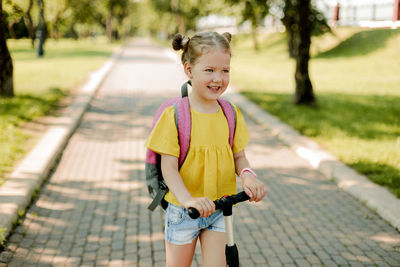 Portrait of young woman standing on footpath