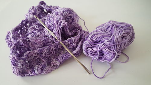 Close-up of purple wool with knitting needle on table