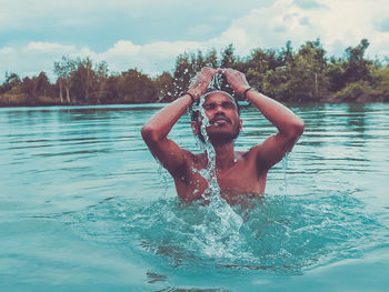 Portrait of shirtless young man in swimming pool