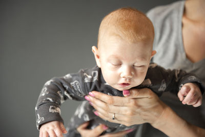 A close-up portrait of a newborn baby, which the mother holds on her arms