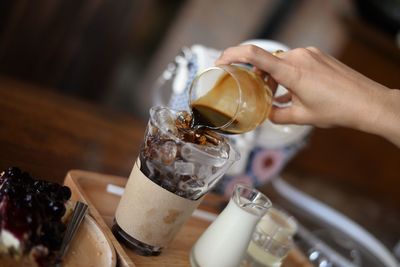 Close-up of hand holding drink on table