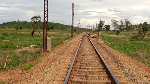 Railroad track amidst field against sky