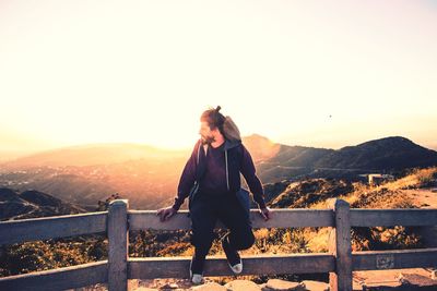 Man sitting on railing against mountain