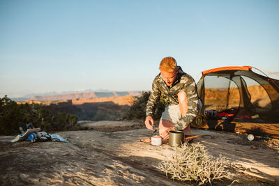 Camper in camo builds a camp stove whisper late preparing for dinner