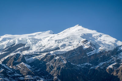 Scenic view of snowcapped mountains against clear blue sky