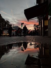 People in front of building against sky during sunset