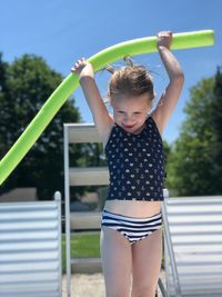 Cute girl holding noodle float while standing in yard