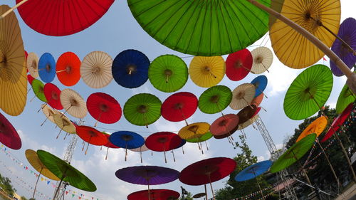 Low angle view of multi colored umbrellas hanging against sky