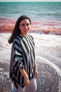 Portrait of young woman standing at beach