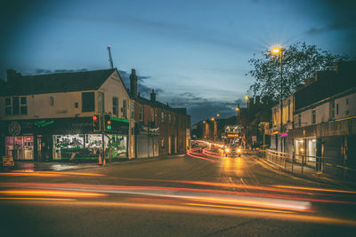 Light trails on street amidst buildings in city at night