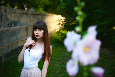 Close-up of flowers against young woman standing at park