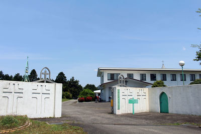 Houses by street against blue sky