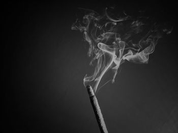 Close-up of burning incense against black background