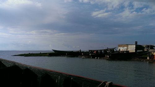 Boats in sea against cloudy sky