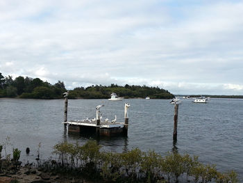 Boats in sea against cloudy sky