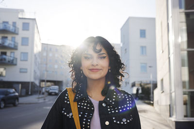 Smiling young woman looking at camera, street in background