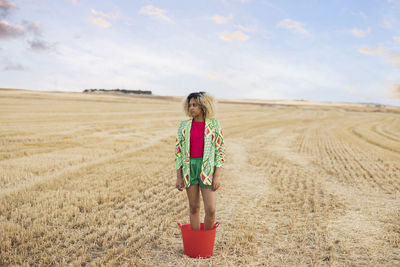 Young woman standing in bucket at field