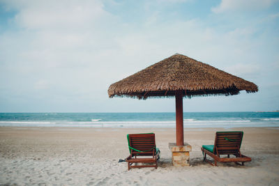 Deck chairs on beach against sky