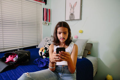 Tween girl takes a serious selfie while wearing a painted on mustache